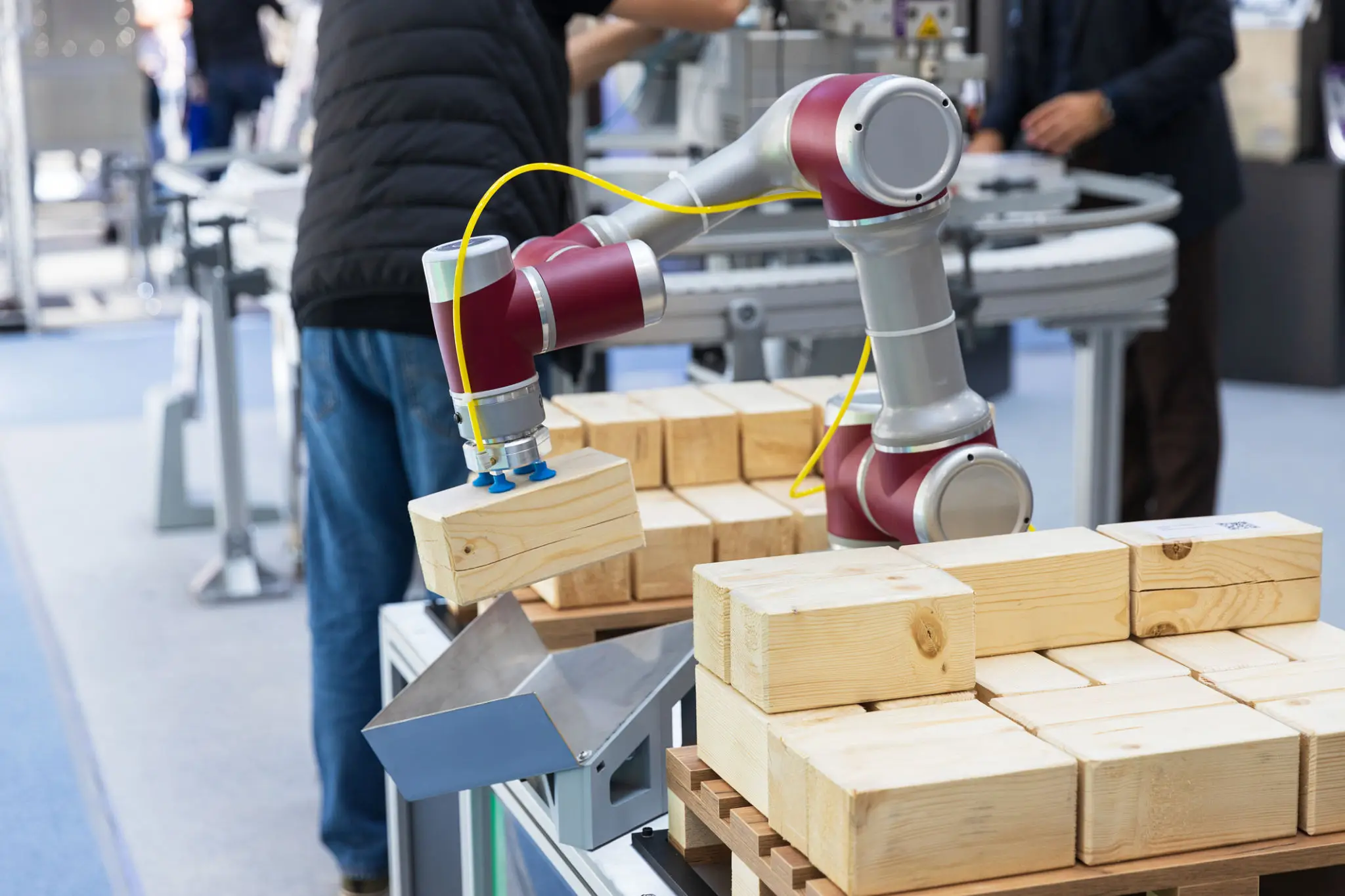 Robotic arm assembling wooden blocks on a production line.