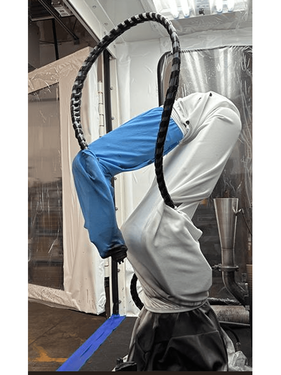Person in blue pants and white hoodie hanging upside down on a hoop.
