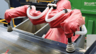 Person in protective suit using a tool on a metal surface.