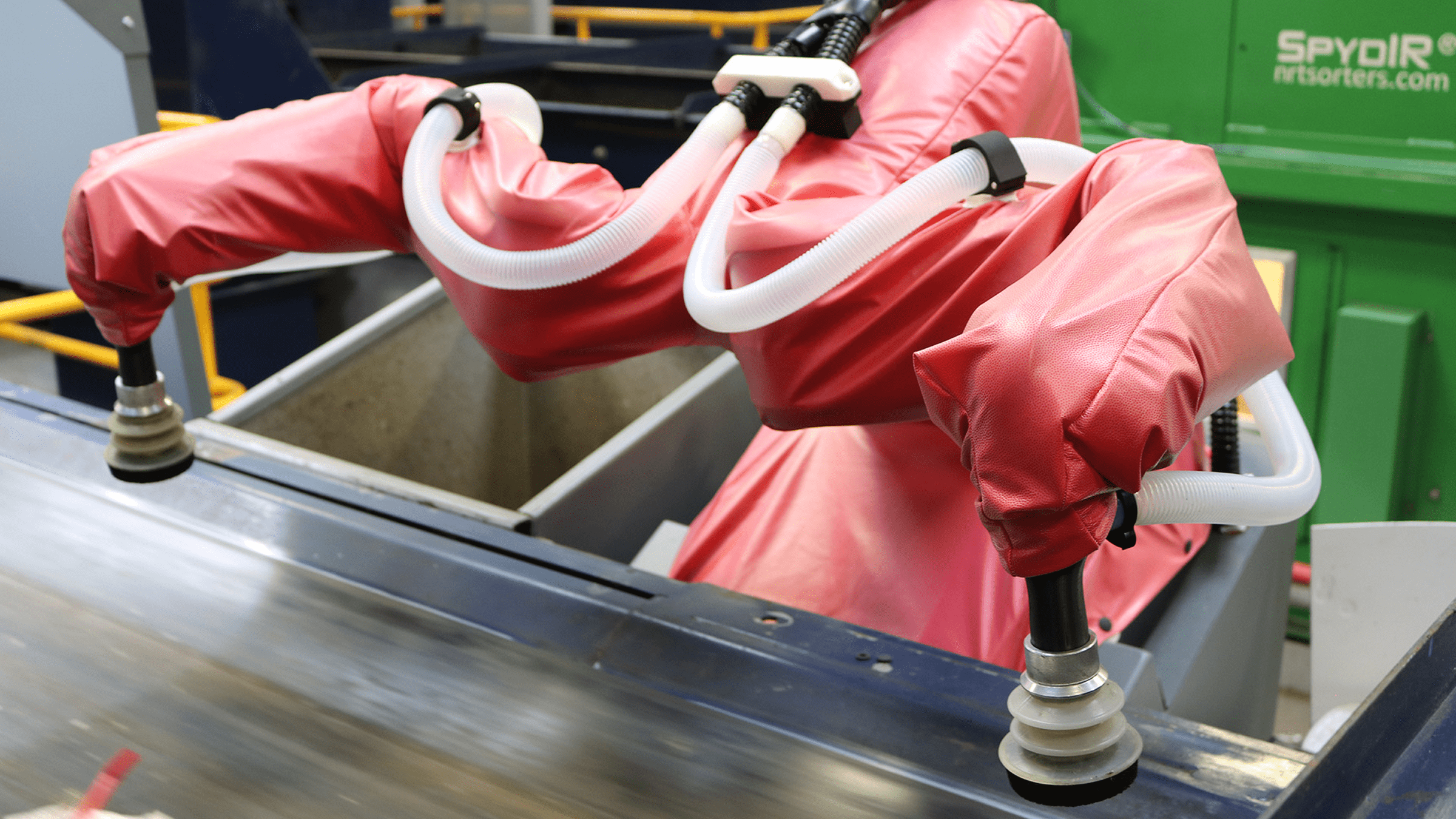 Person in protective suit using a tool on a metal surface.